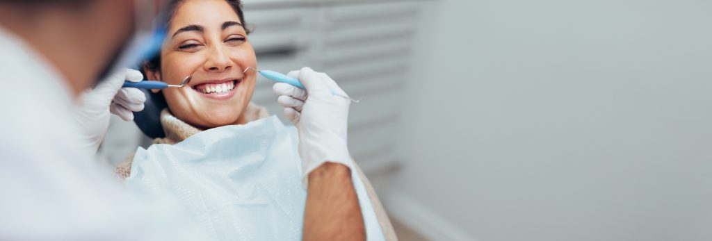 A dentist examining a patient's teeth with a dental mirror and probe.