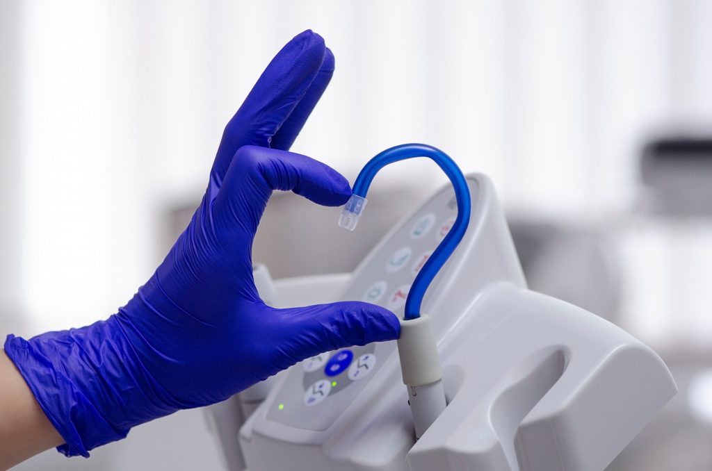 Person in purple gloves holding heart-shaped tube.