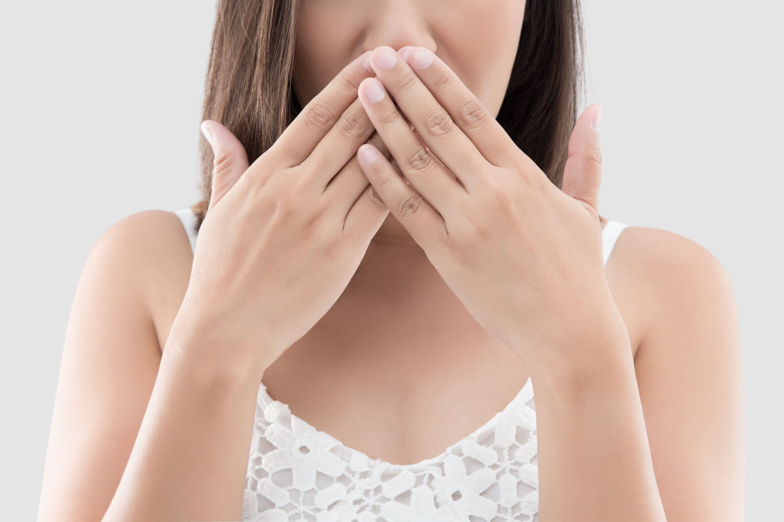 Woman with hands covering mouth, indicating embarrassment or bad breath