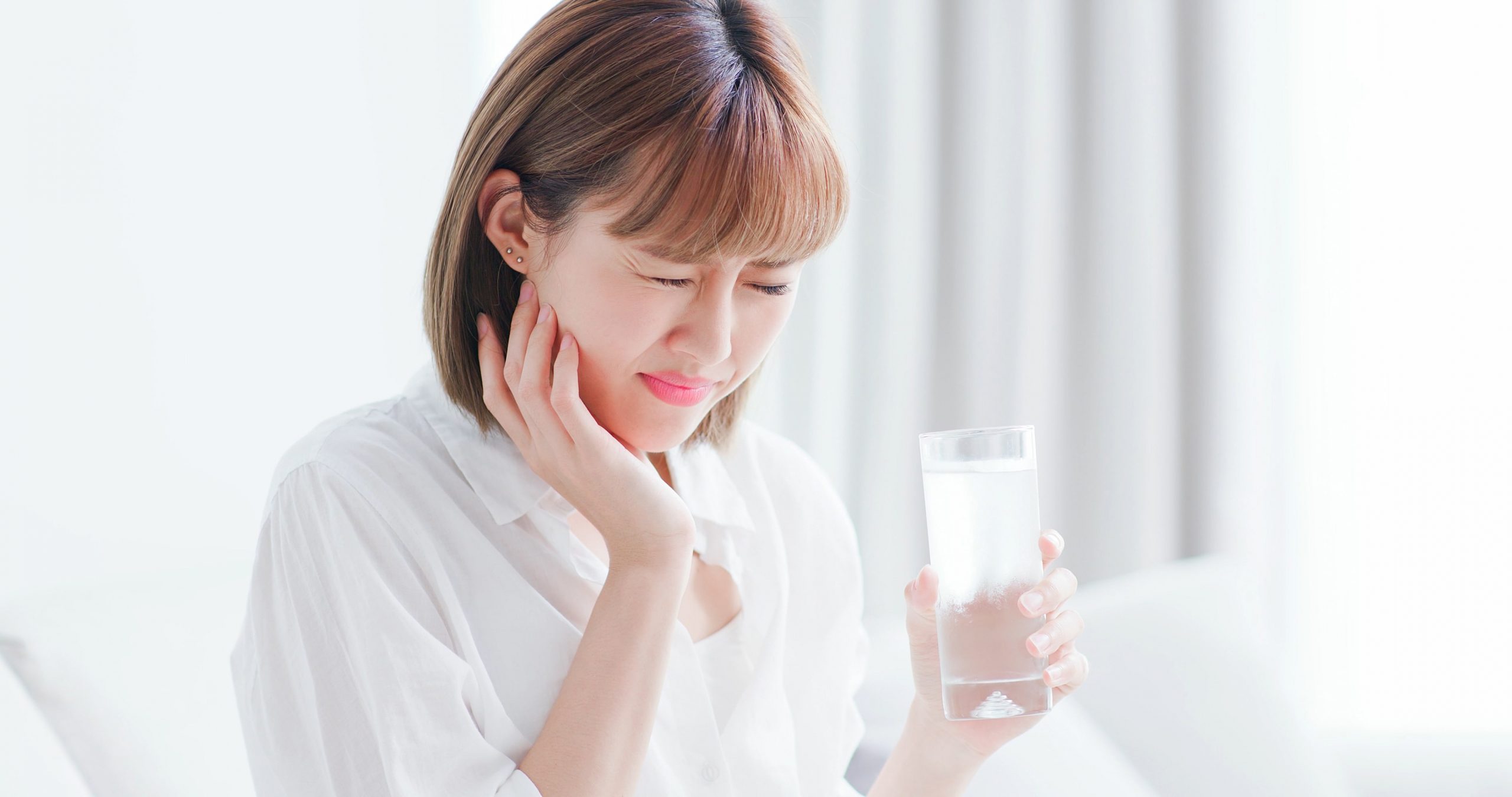 Image of a woman with tooth sensitivity, and signs of discomfort.