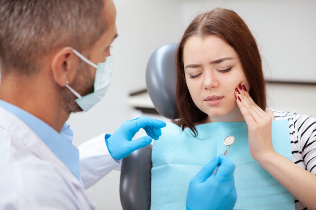 Woman receiving dental check-up from dentist, addressing toothache.