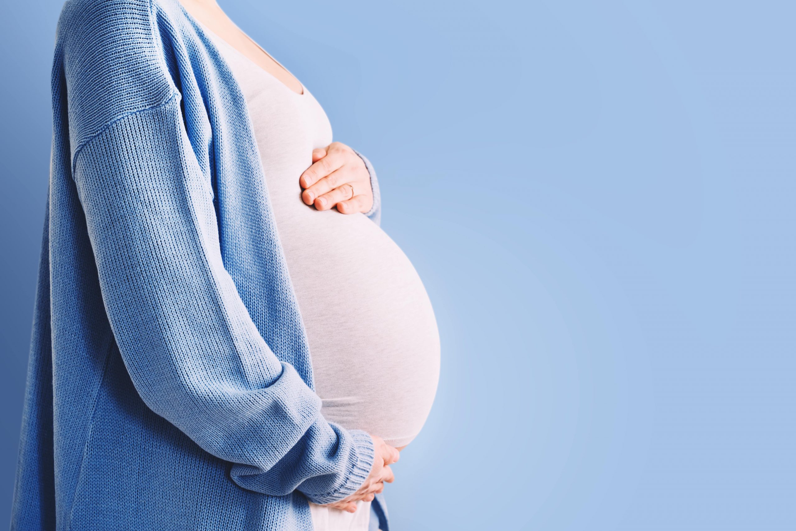 stock photo of a pregnant woman wearing a blue sweater and jeans.