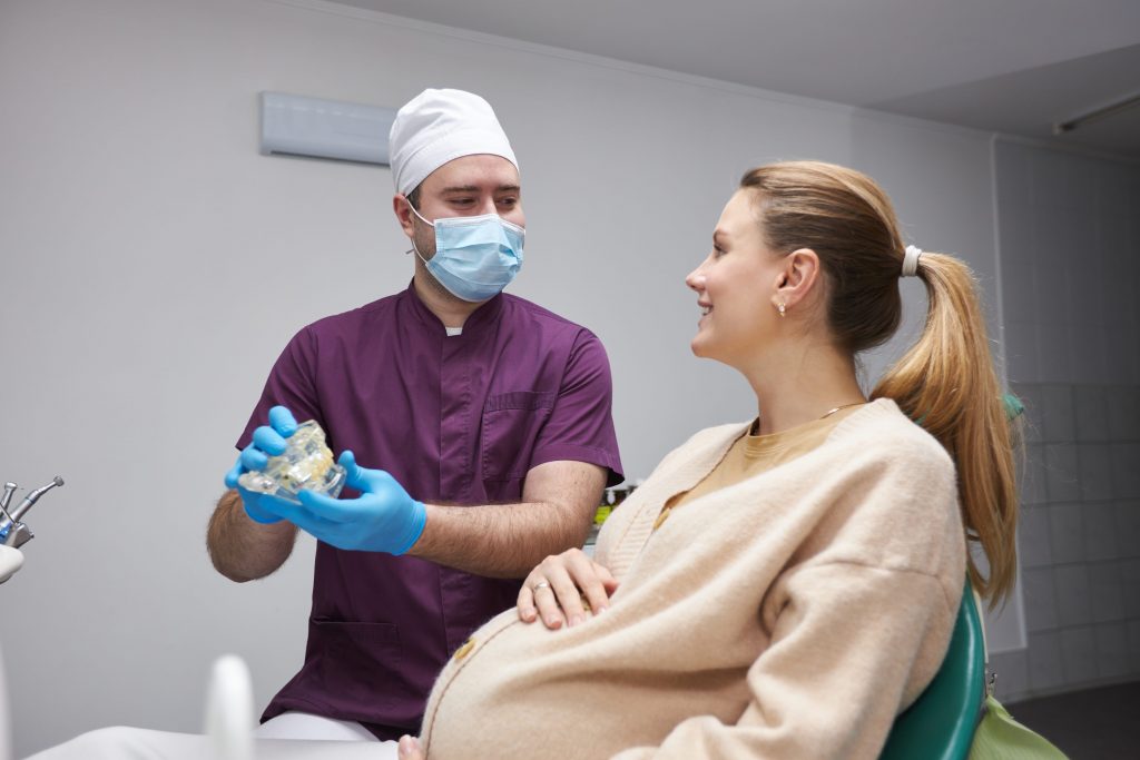 A pregnant woman sitting in a dentist's chair during a check-up.