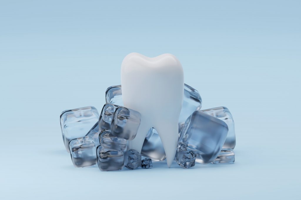 Tooth and ice cubes on blue background